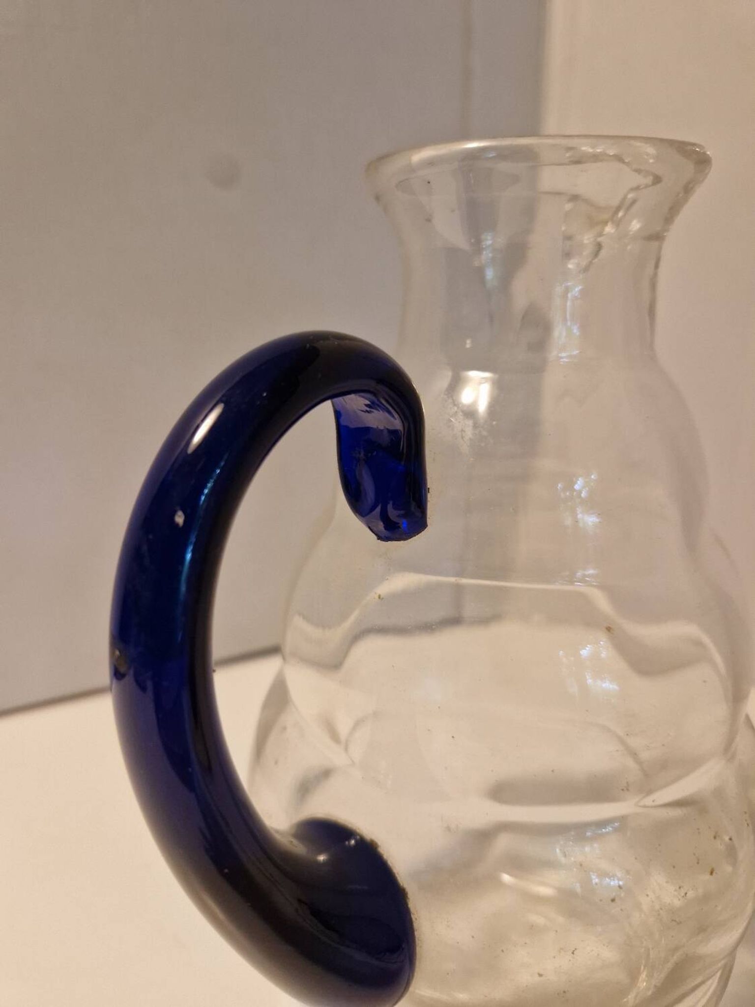 Glass carafe with wavy body and blue handle