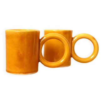 Pair of ceramic coffee cups with large circular handles yellow