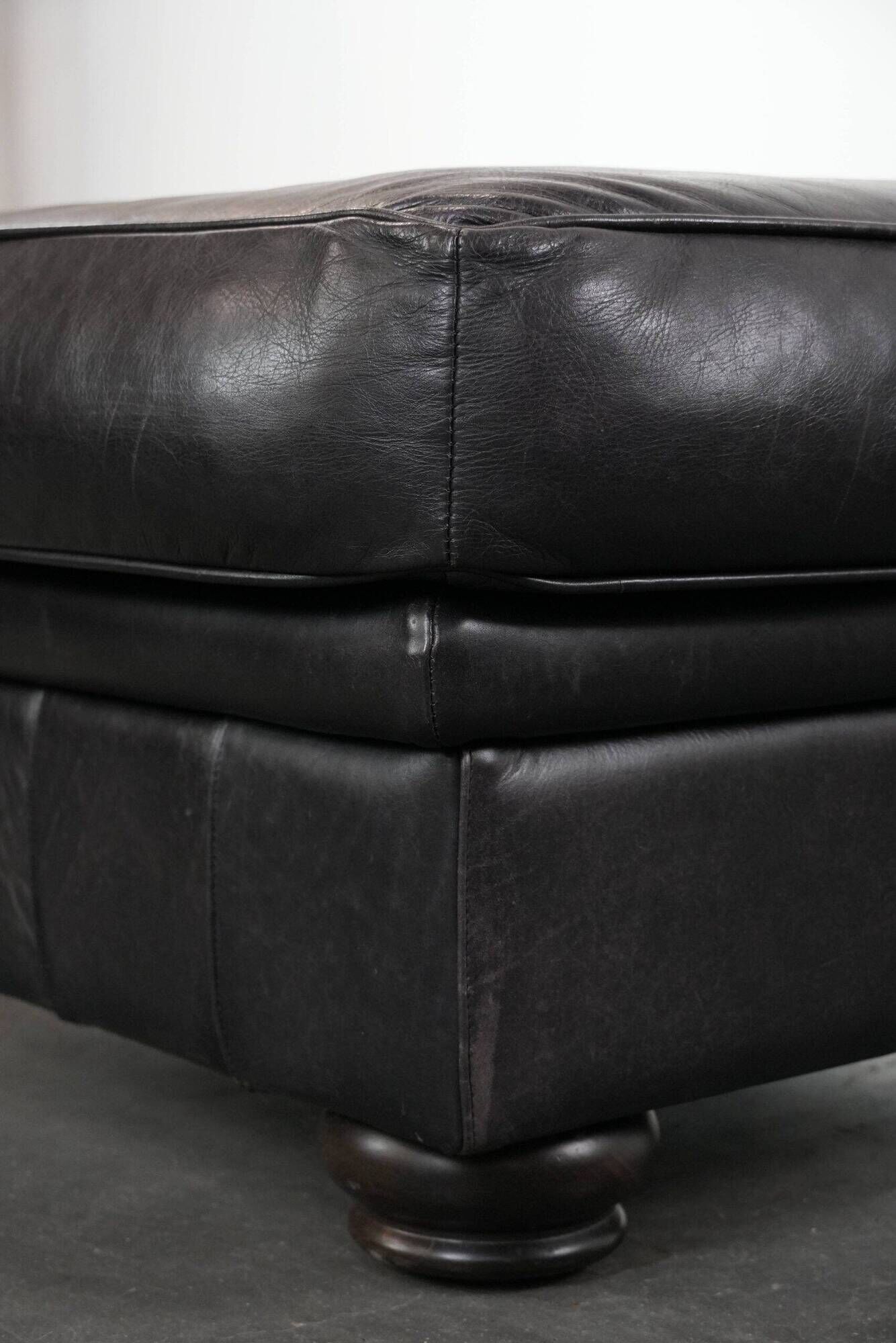 Set of a black cowhide leather Chesterfield armchair and matching ottoman