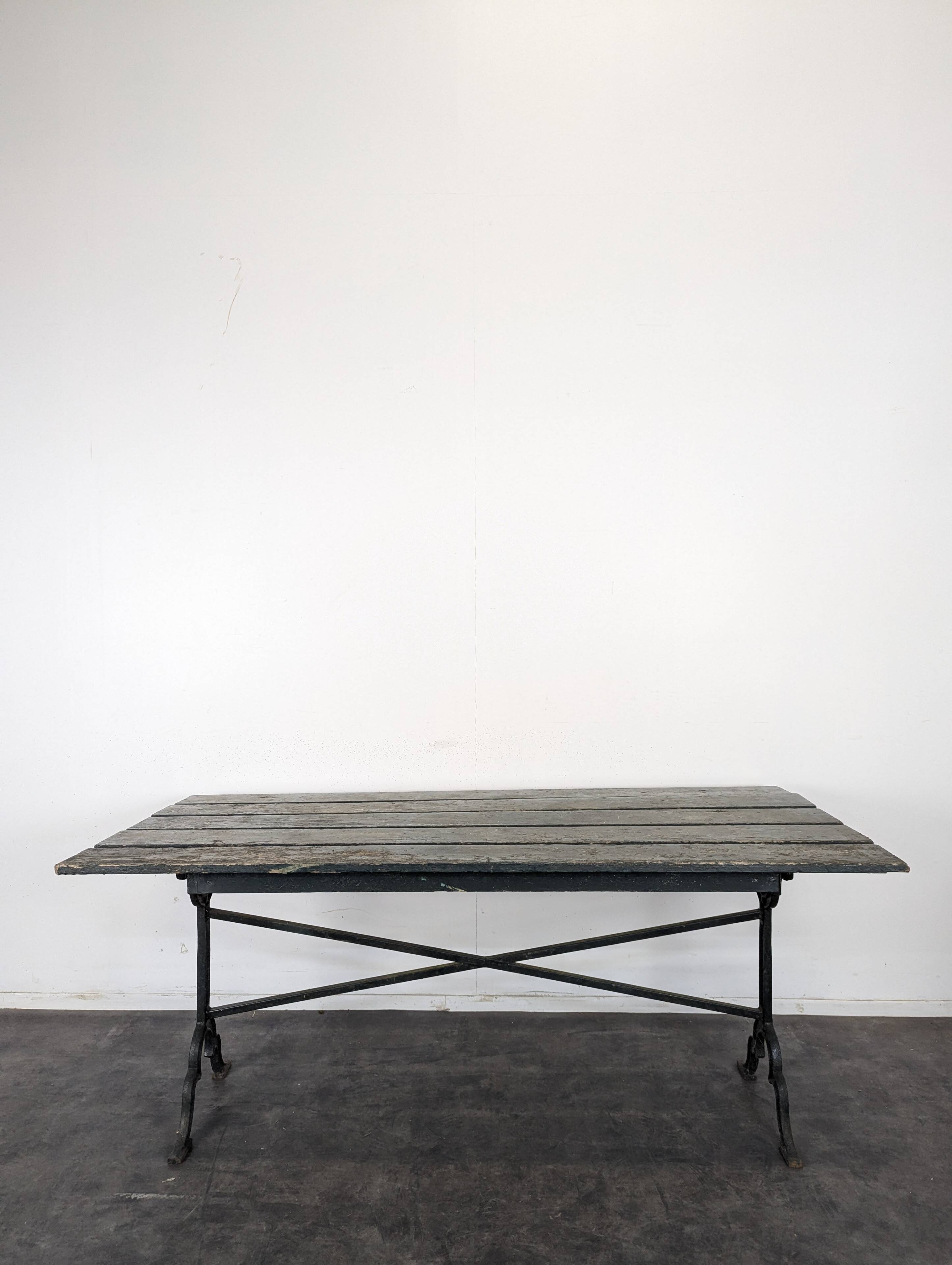 Garden table with a cast iron base and a green painted wooden top.