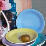 Seven pastel-colored plates mixed with vintage earthenware