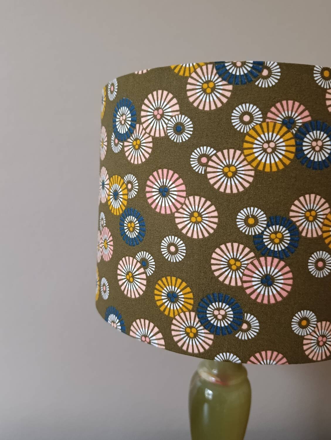 Table lamp with light green onyx base, fabric shade with a khaki background.