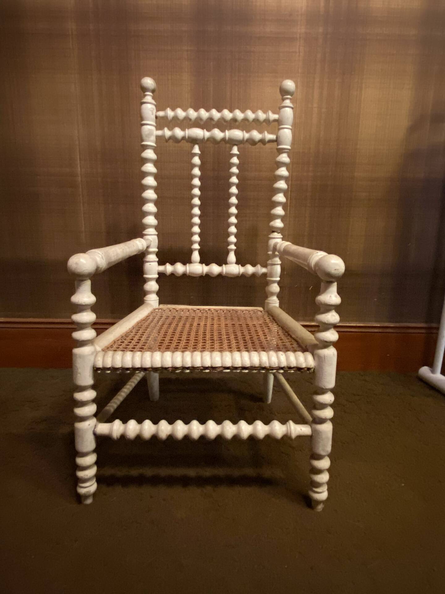Antique wooden child's chair with turned legs and caning, white patina.