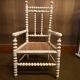 Antique wooden child's chair with turned legs and caning, white patina.