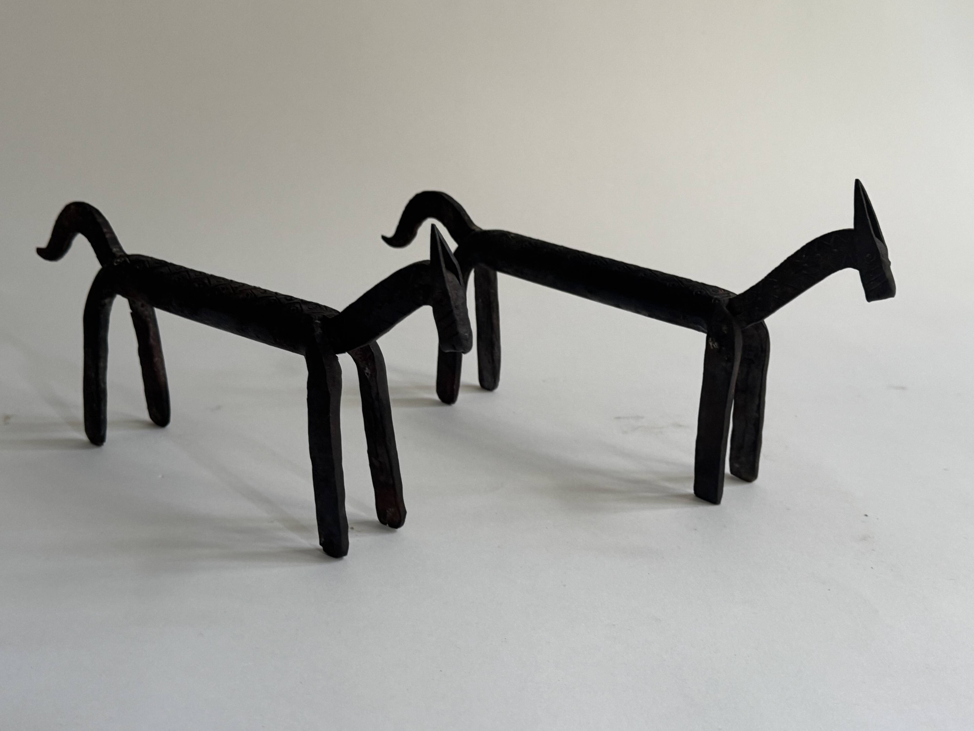 Pair of animal-shaped wrought iron and hammered fire dogs in primitive brutalist style.