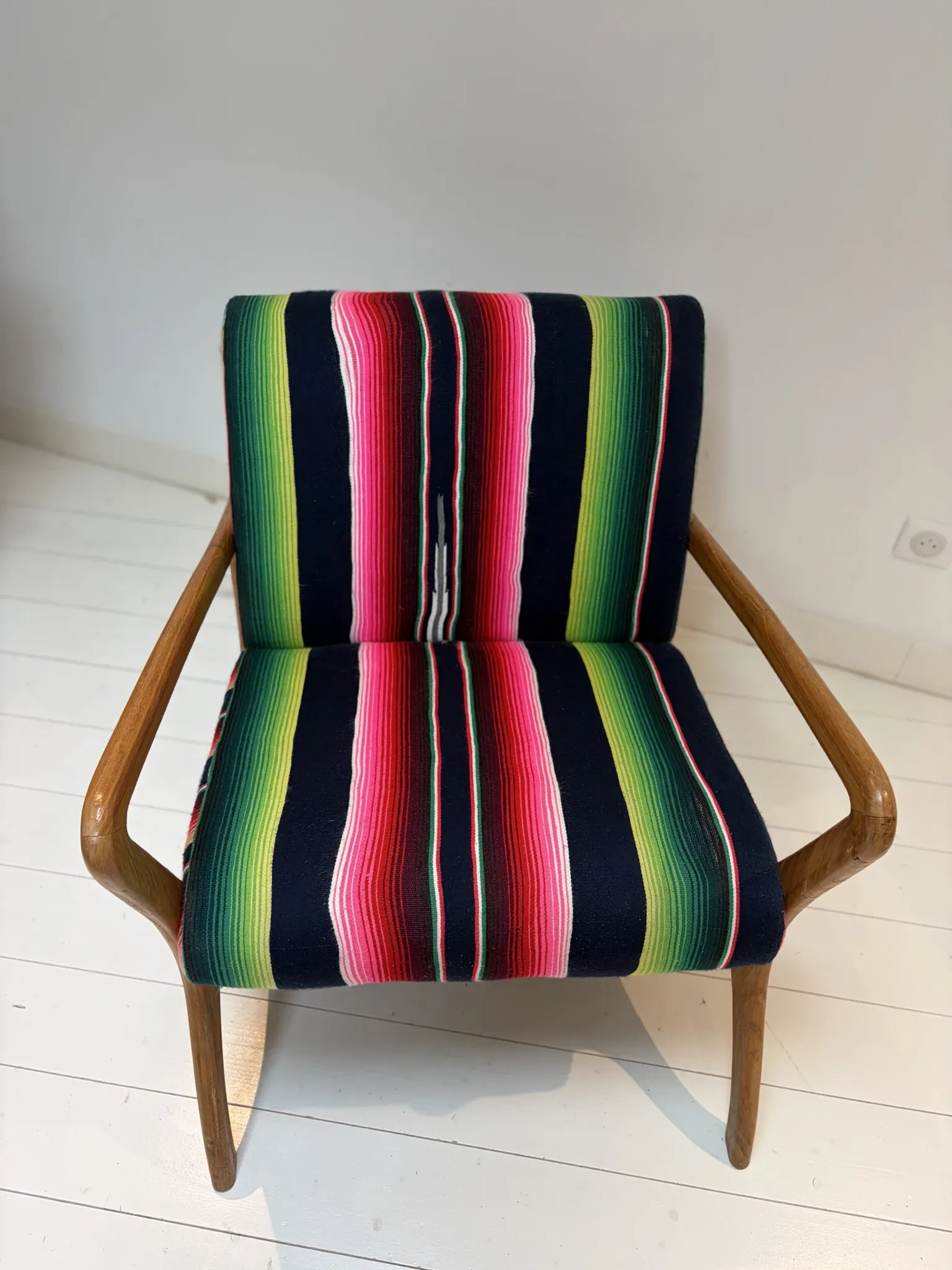 Scandinavian-style armchair in curved wood and colourful striped fabric.