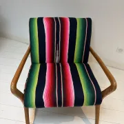 Scandinavian-style armchair in curved wood and colourful striped fabric.