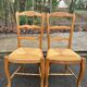 2 solid wood and rush-seated chairs in Louis XV style with shell carving from the 20th century.