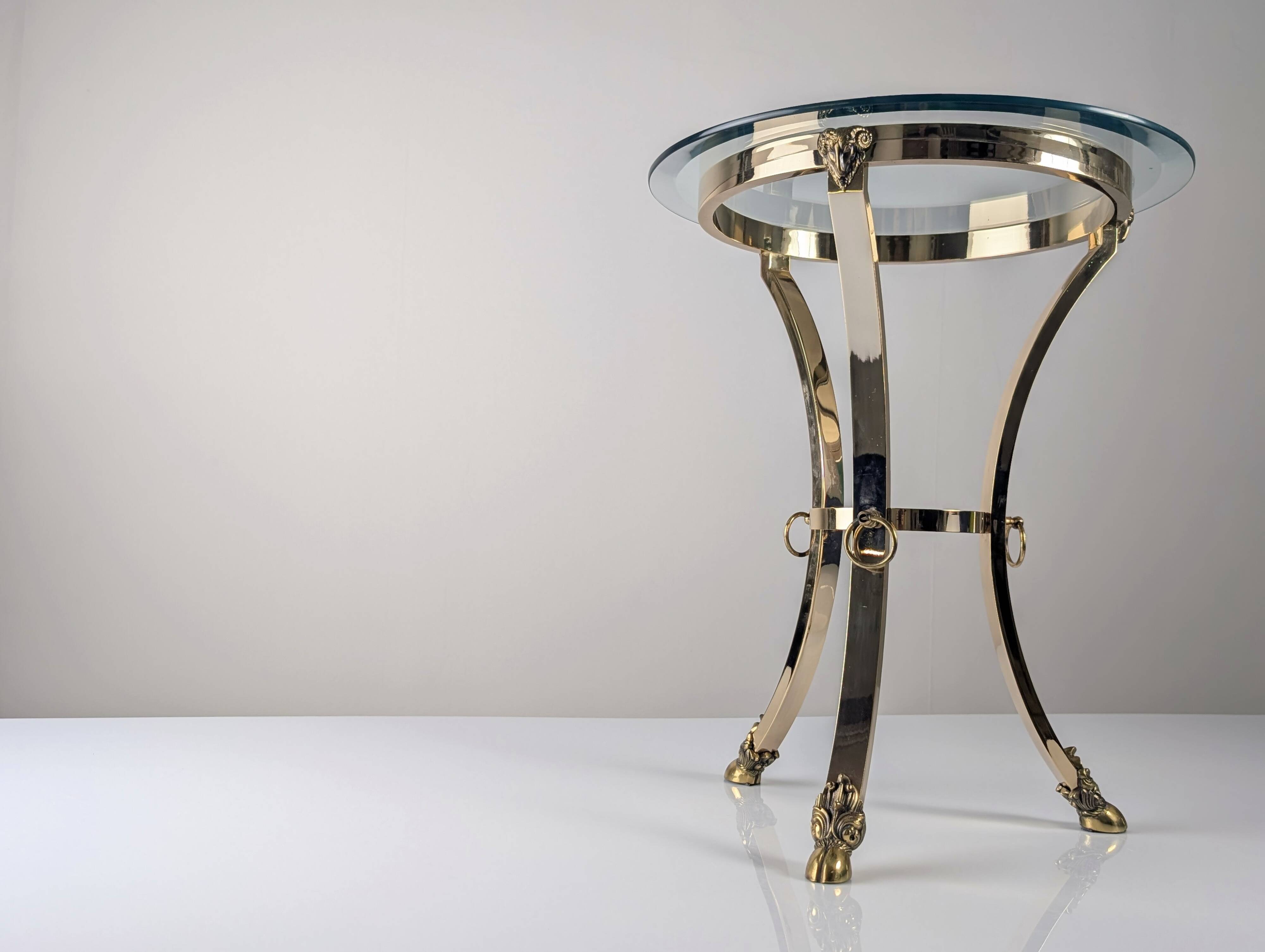 Neoclassical side table in brass and bevelled glass with ram's heads, 1970s.