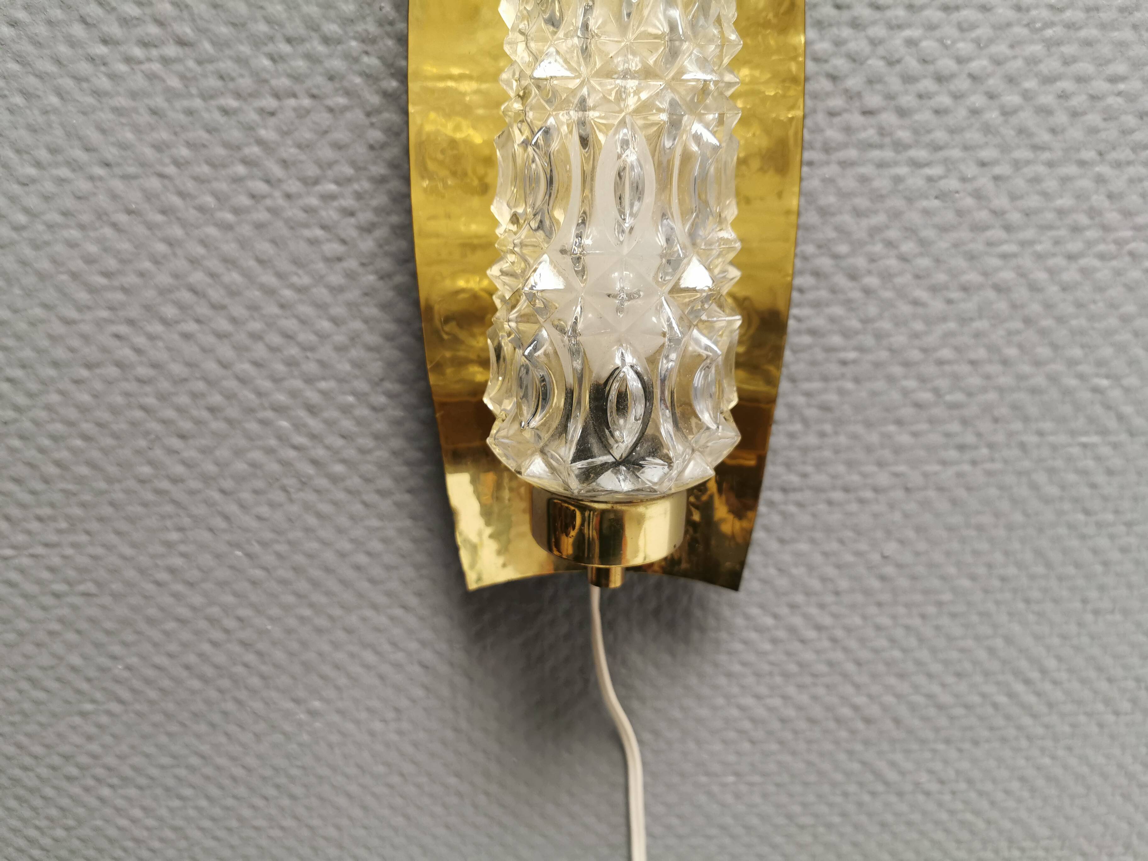 Older wall lamp in brass with hard pressed glass shade.