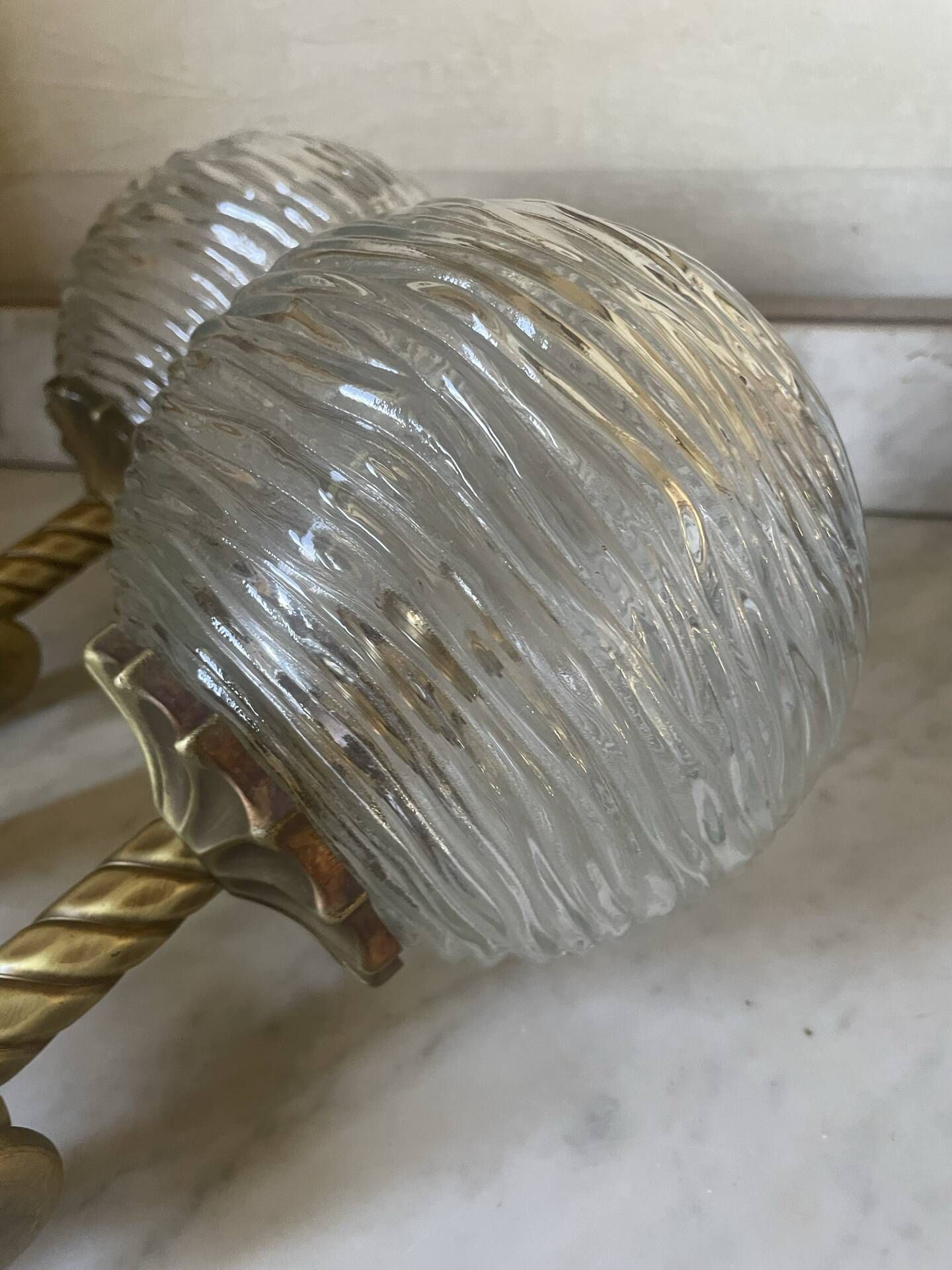 Pair of neoclassical wall sconces in twisted brass and ribbed glass.