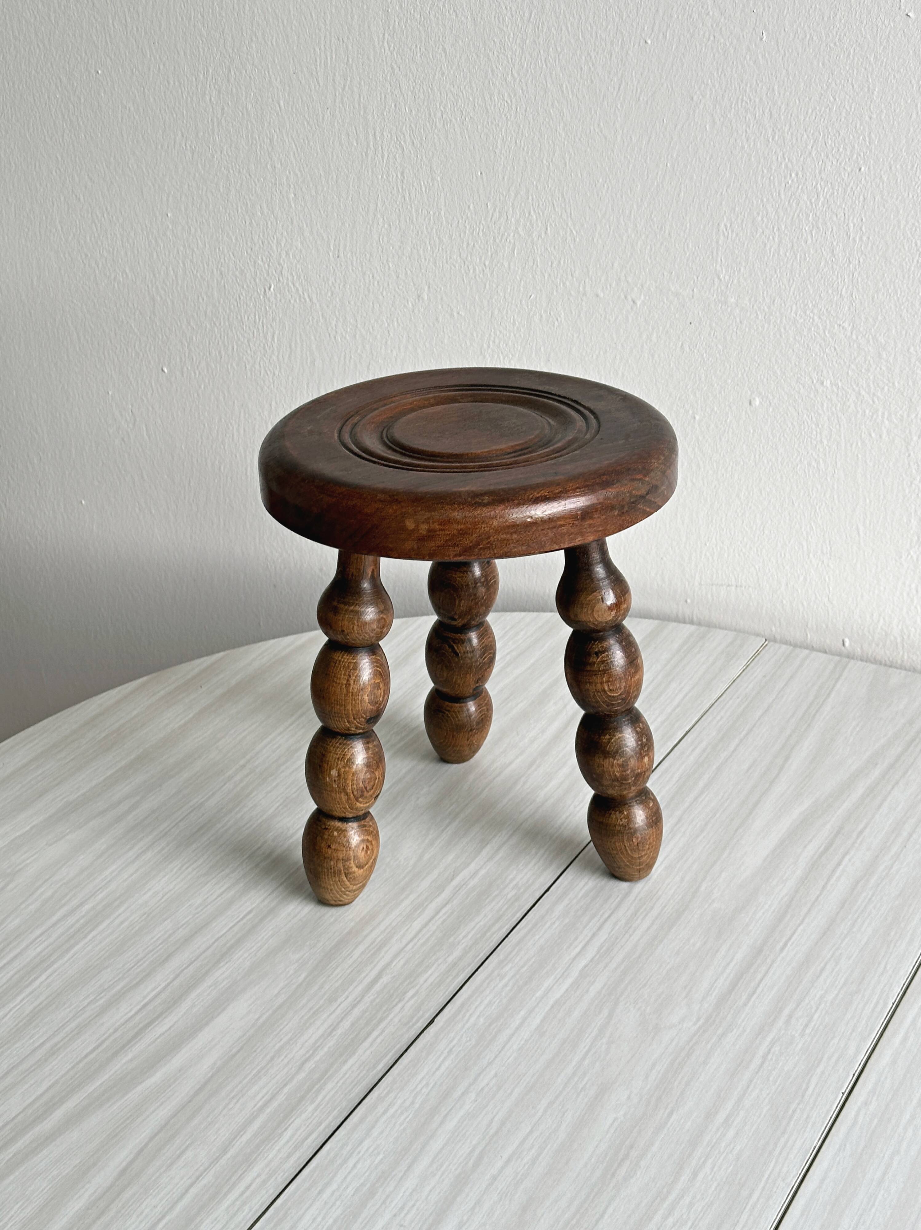 Small three-legged stool made of turned wood.