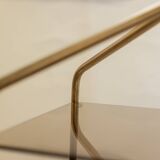 Free-standing shelf in gilded brass with smoked glass shelves. 1970s.