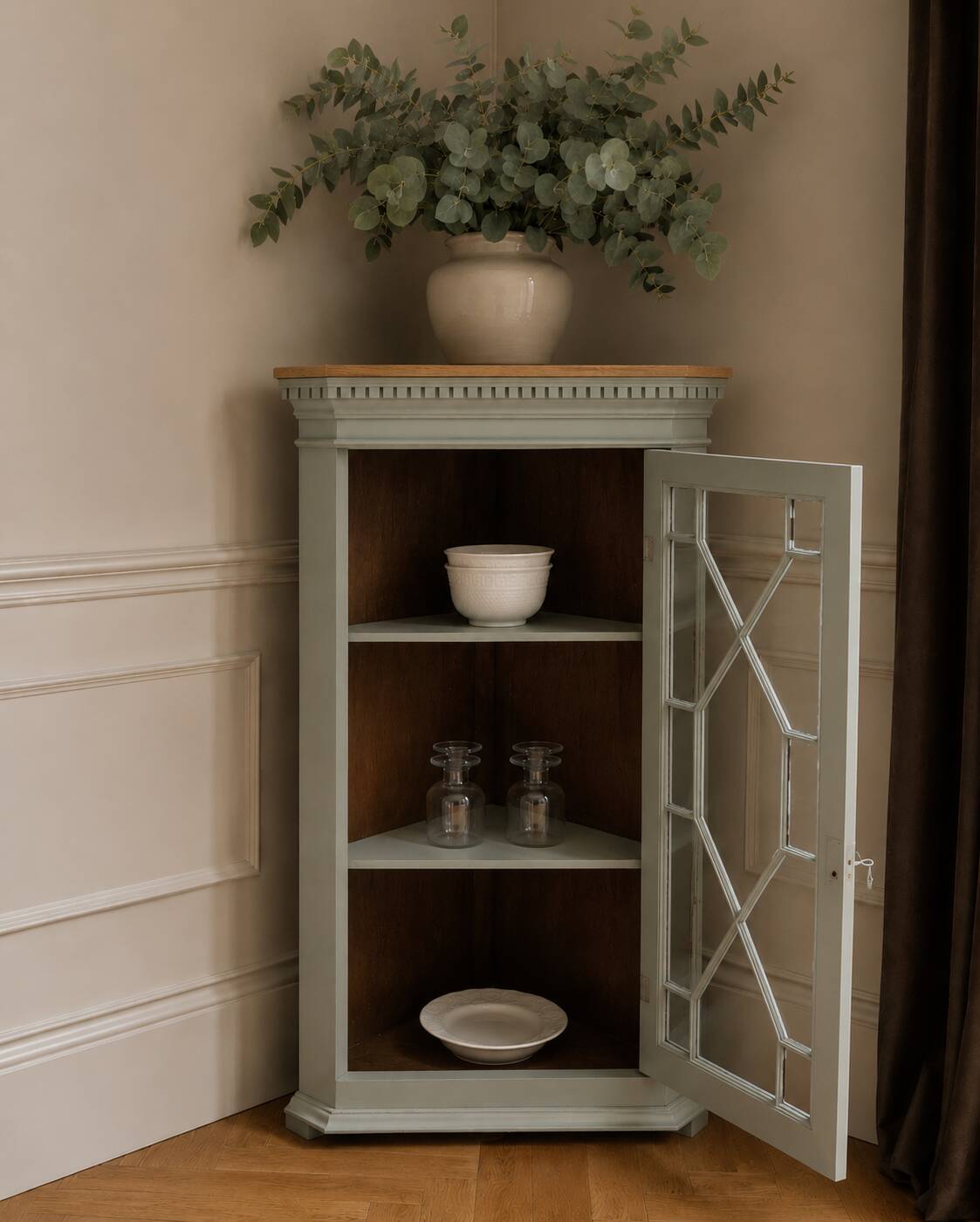 Vintage English corner display cabinet enhanced in grey-green with a wooden top.