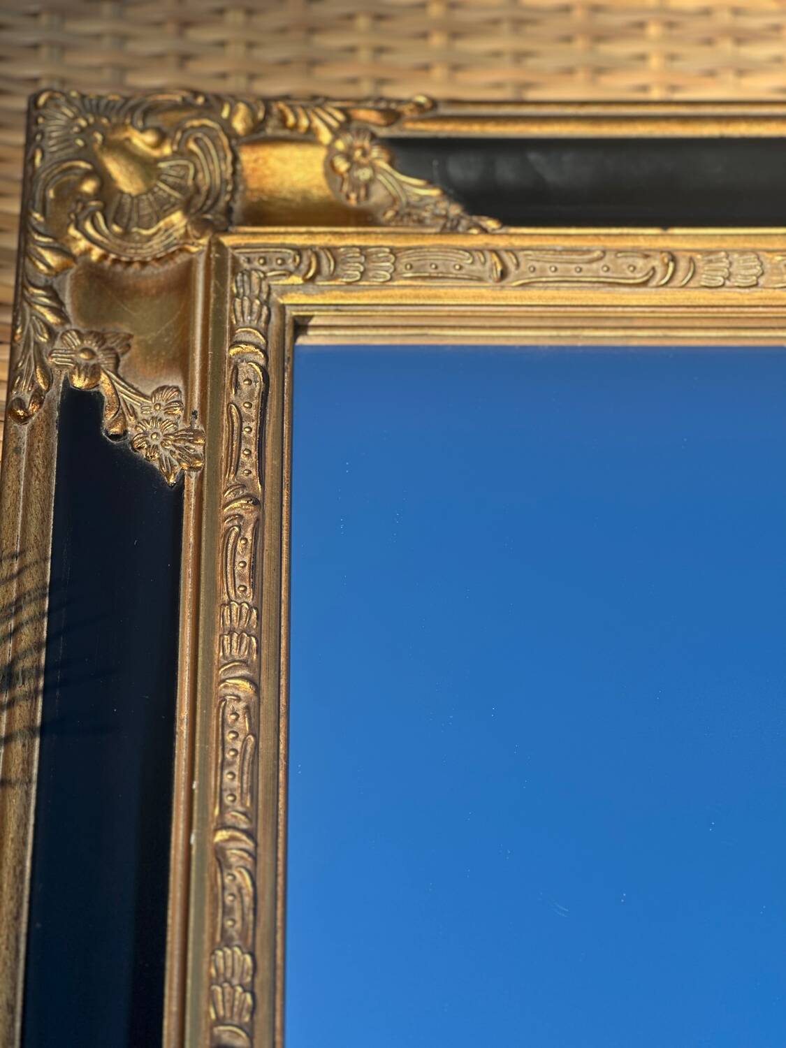 Baroque mirror in gilded wood on a black background.