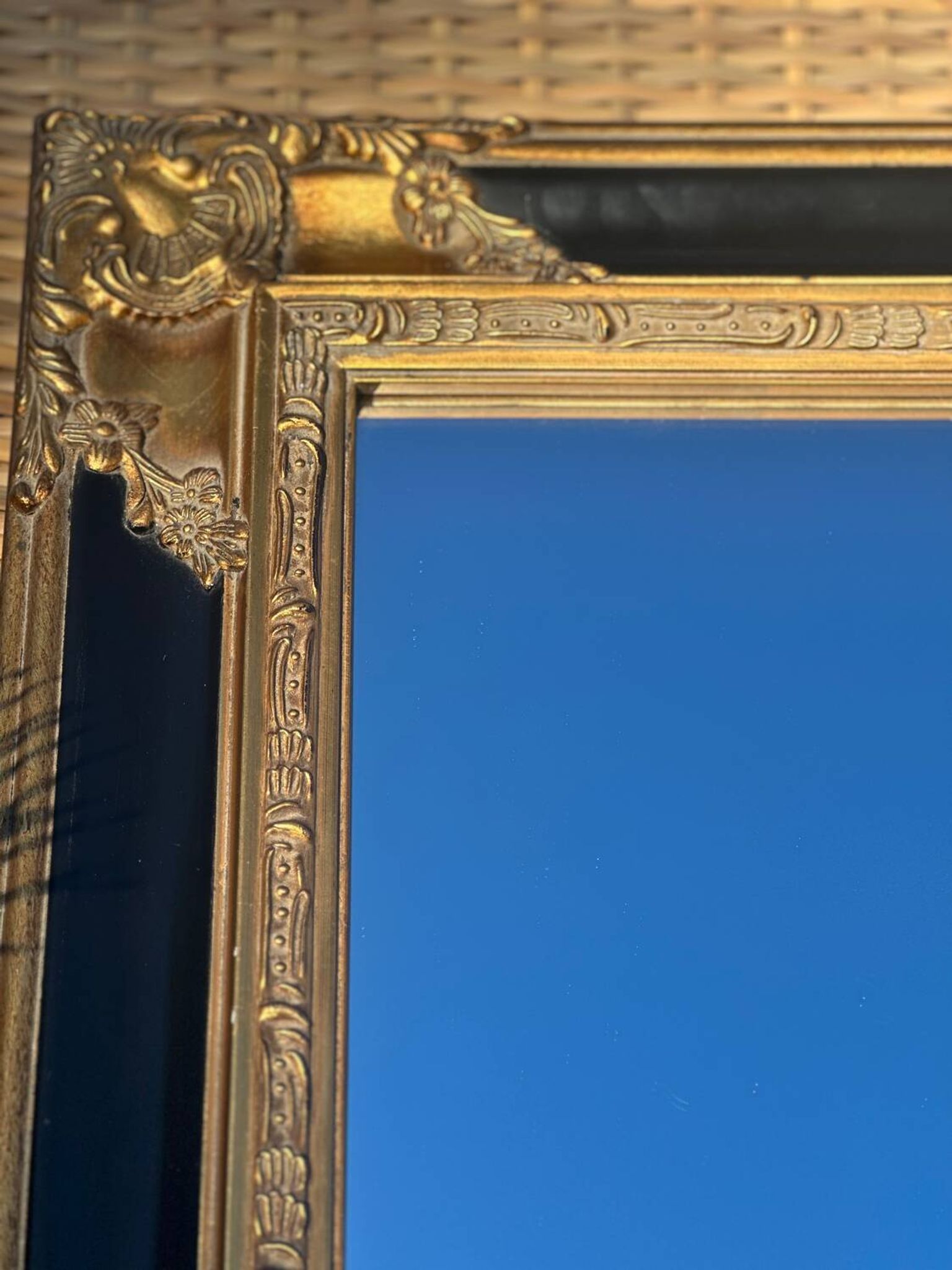 Miroir Baroque en bois doré sur fond noir.