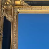 Baroque mirror in gilded wood on a black background.