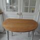 Walnut table with raised flaps, base on verdigris casters.