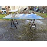Vintage table with a glass top and smoked plastic trestle legs.