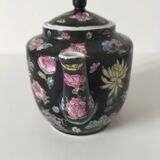 Vintage Chinese teapot with floral polychrome decoration on a black background.
