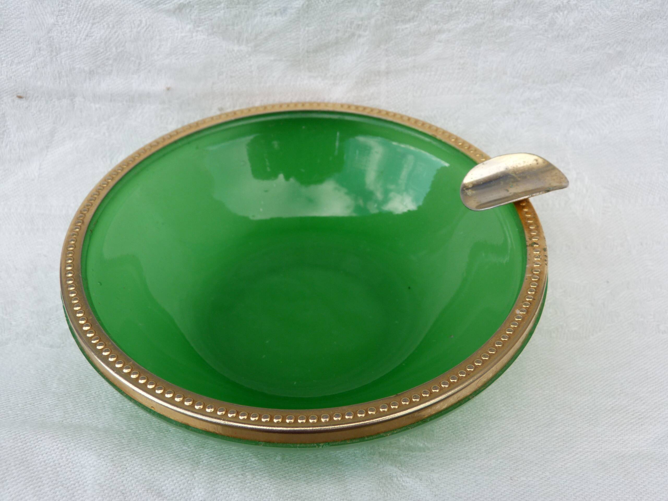 Green glass ashtray set in gold brass