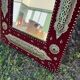 Large oriental mirror with embossed brass decoration on a red velvet background