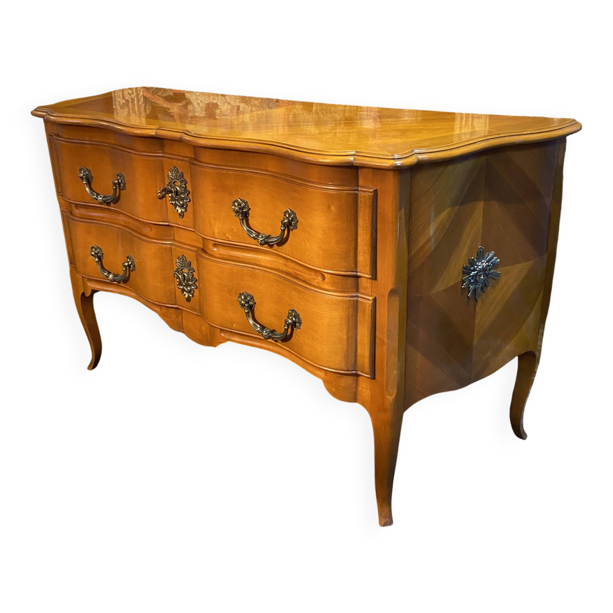 Large bow-fronted chest of drawers in blonde cherry with bronze ornamentation.