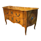Large bow-fronted chest of drawers in blonde cherry with bronze ornamentation.