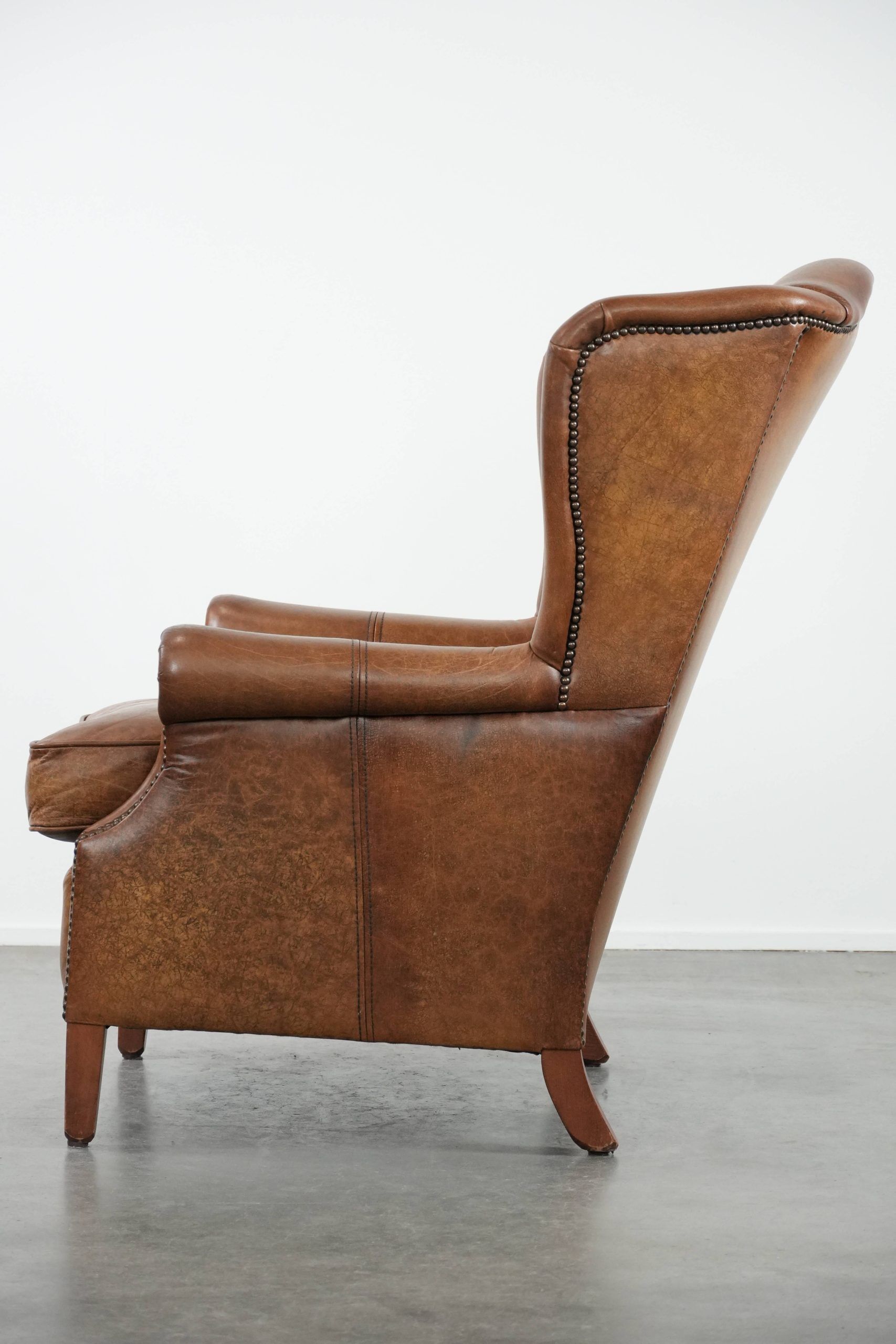 Cognac-coloured wingback armchair in English style made of cowhide leather
