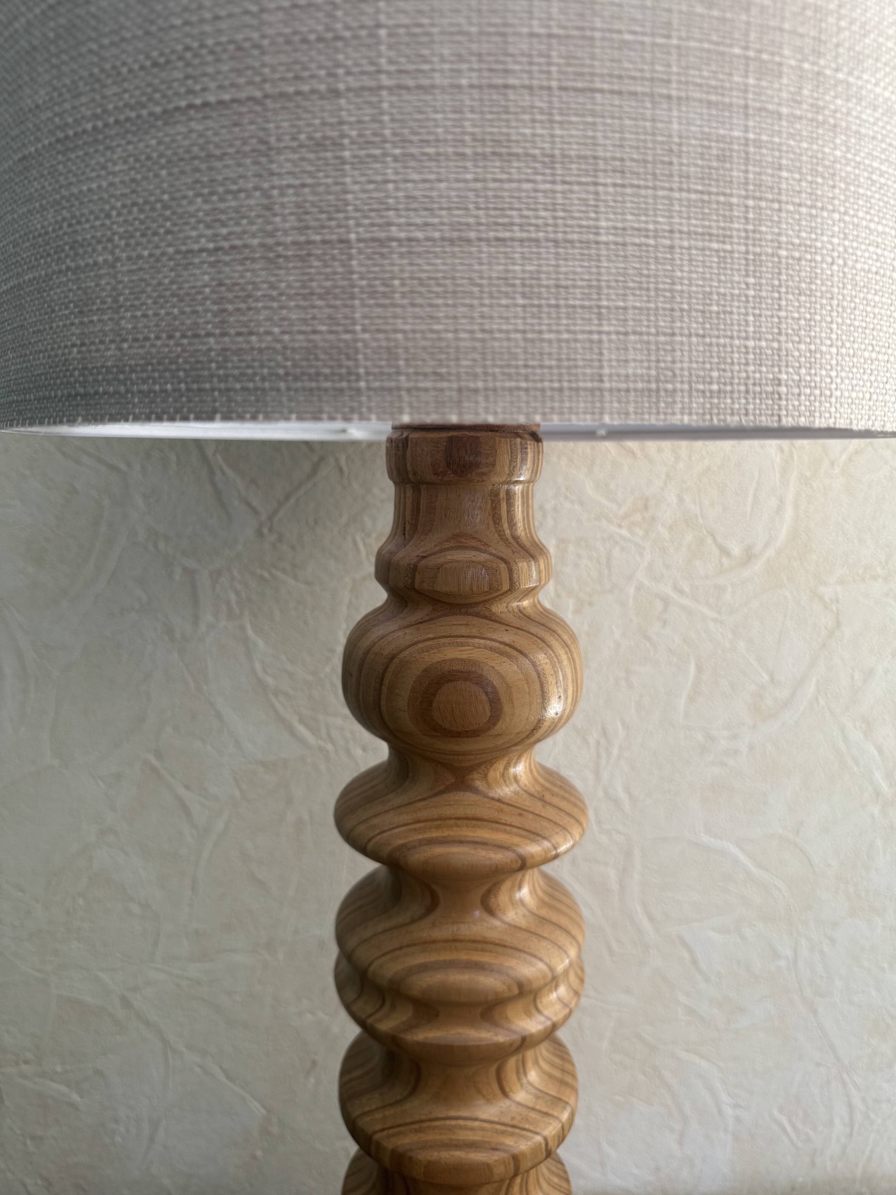 Wooden turned totem lamp with a linen shade in a vintage Scandinavian style.