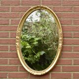 Old large oval wall mirror in golden resin