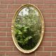 Old large oval wall mirror in golden resin