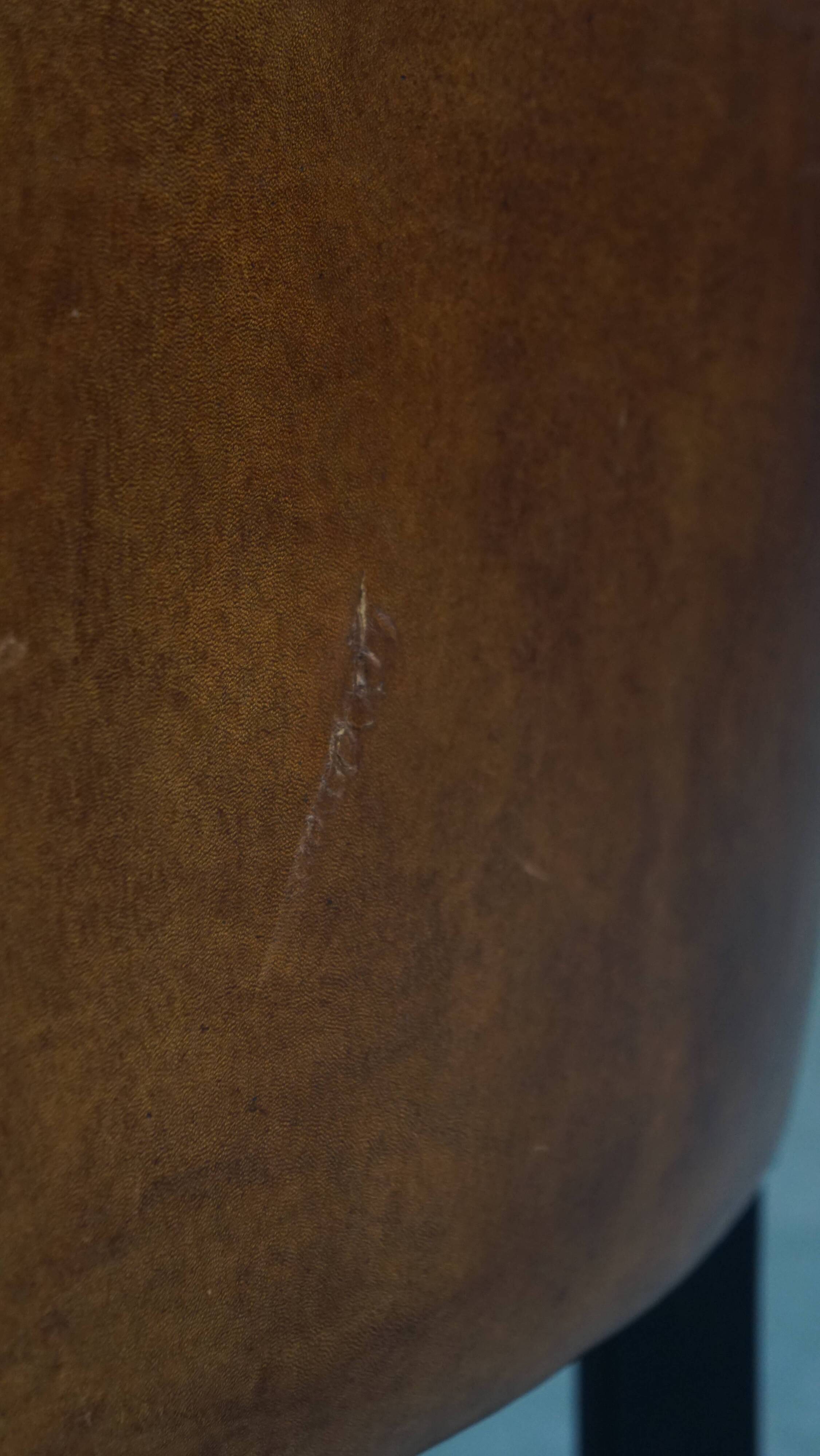 Cognac-colored sheepskin armchair with black piping and decorative nails