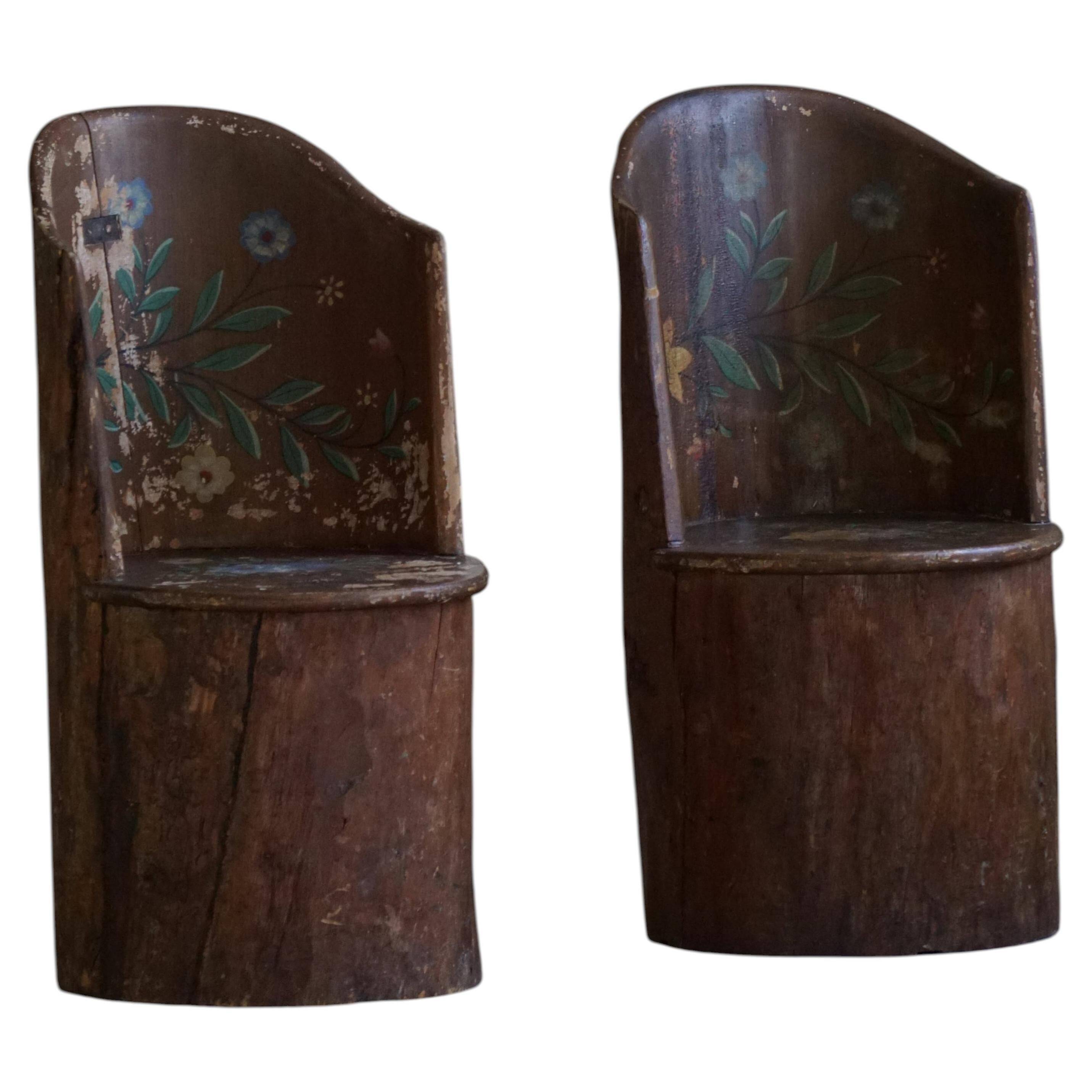 Pair of Swedish folk art stump chairs, decorated with painted floral motifs, late 19th century.