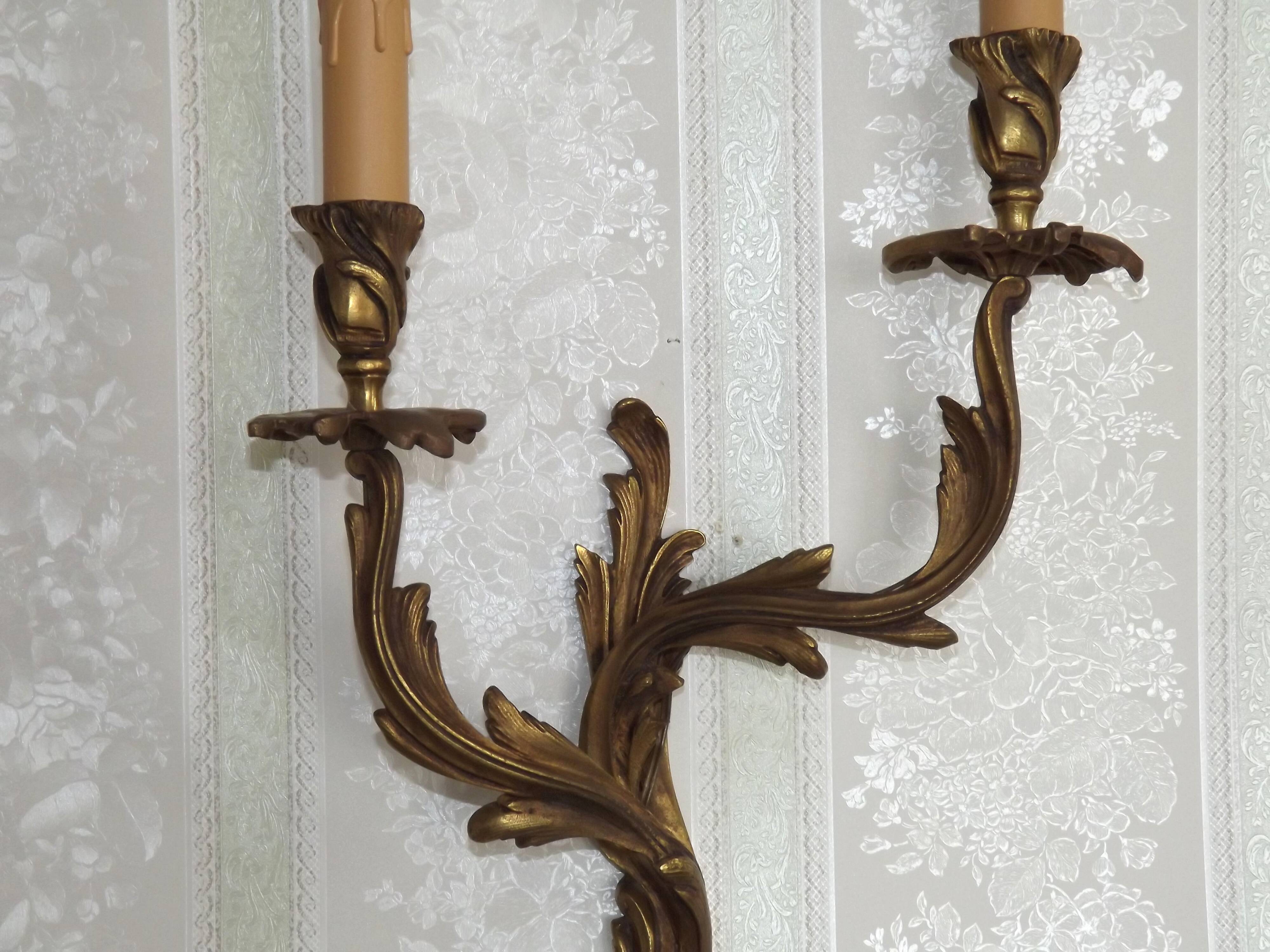 Apply two bronze wall lights decorated with acanthus leaves.