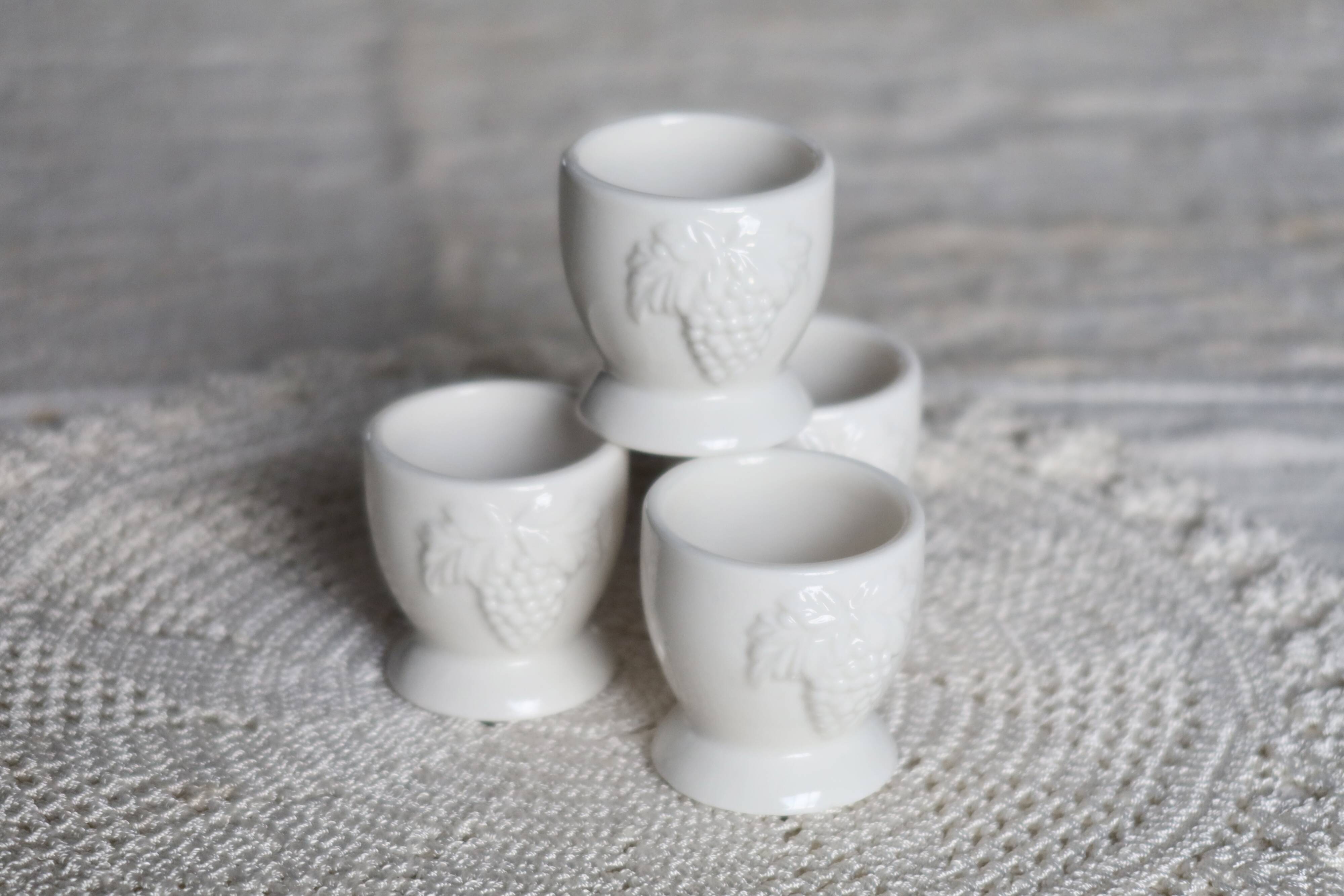 Vintage white porcelain egg cups with fruit motif.