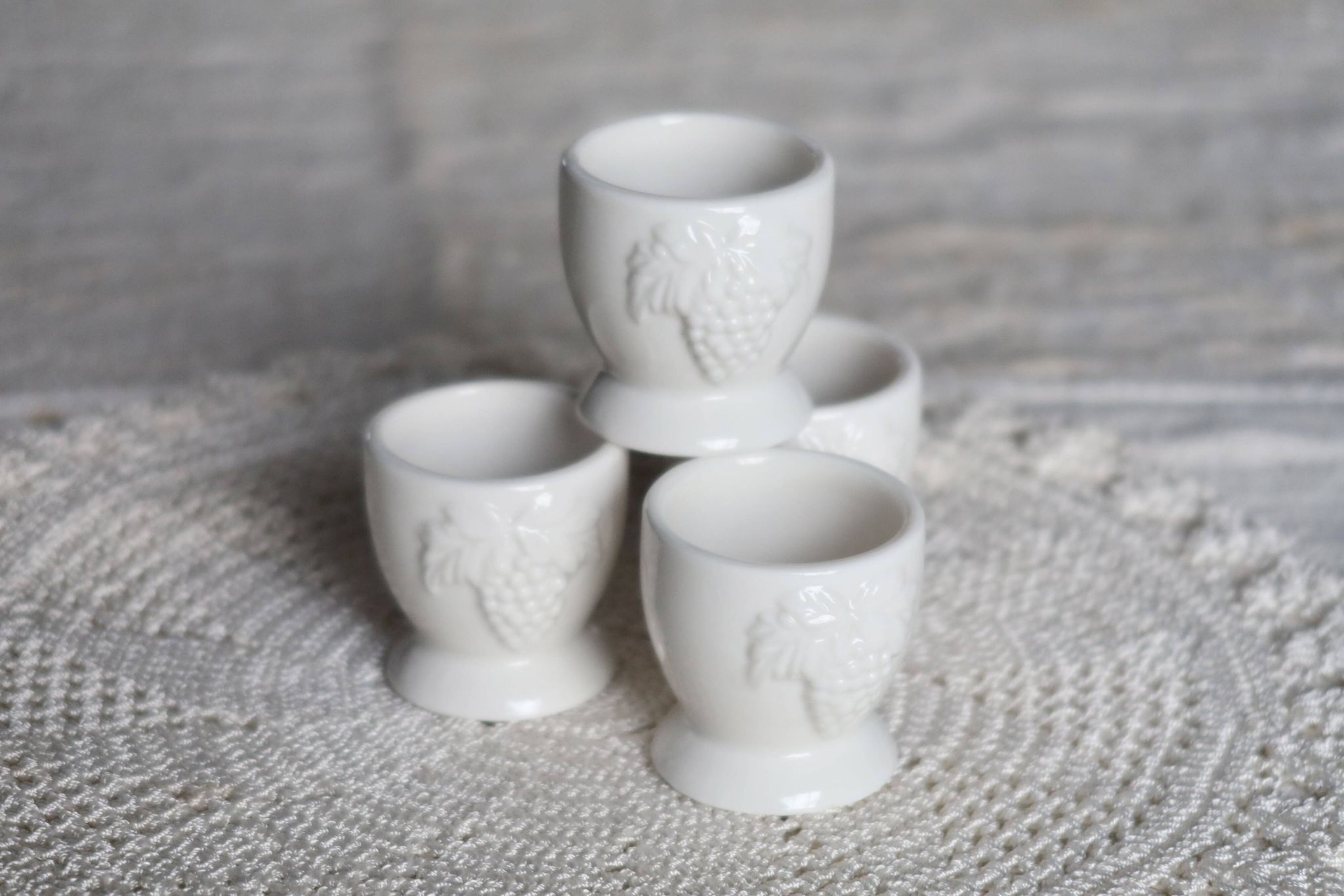 Vintage white porcelain egg cups with fruit motif.