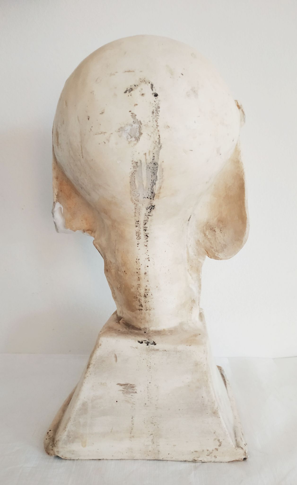 Bust of woman in plaster on pedestal with inscription