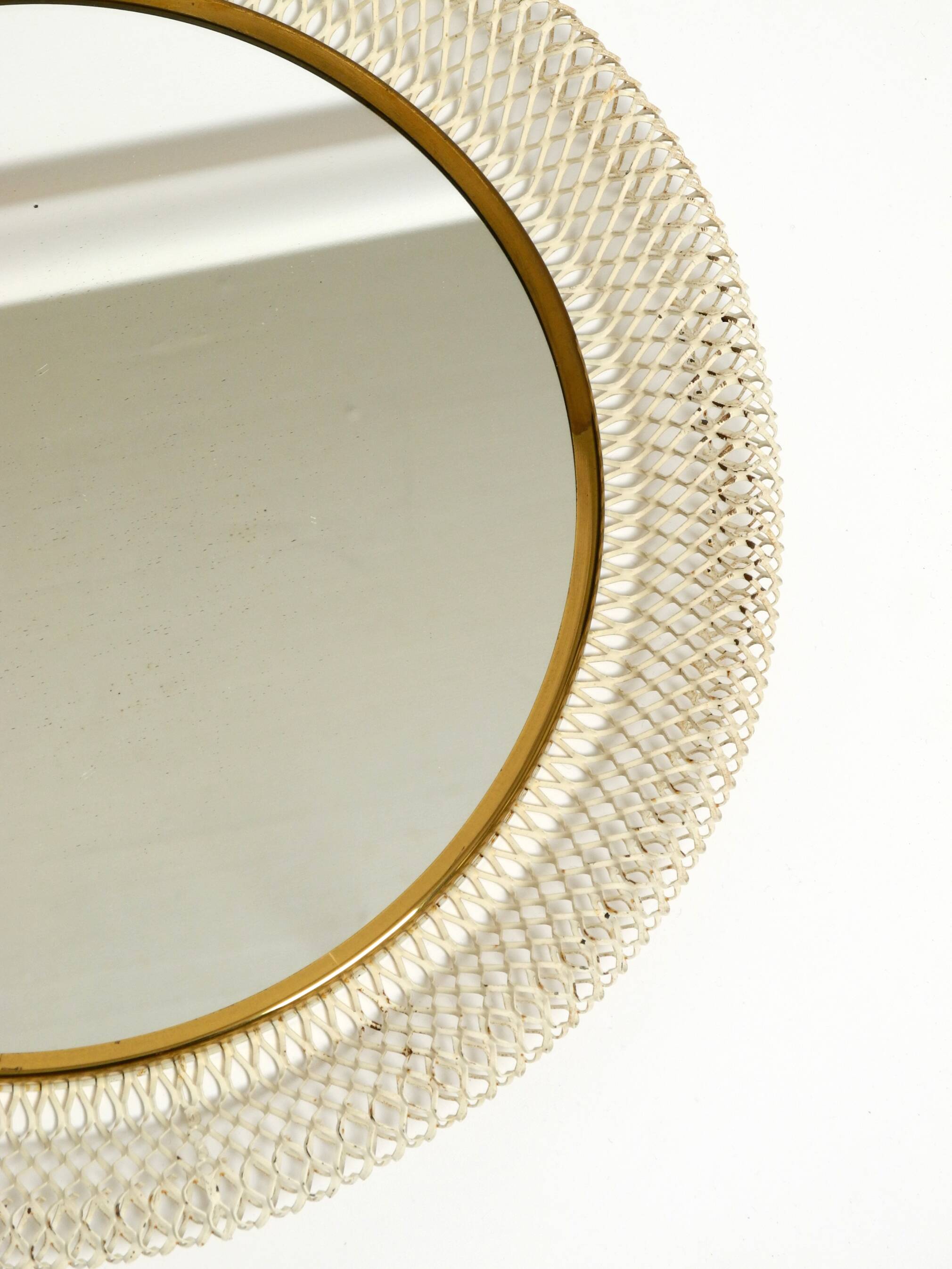 Mid Century Modern round wall mirror with a white expanded metal frame