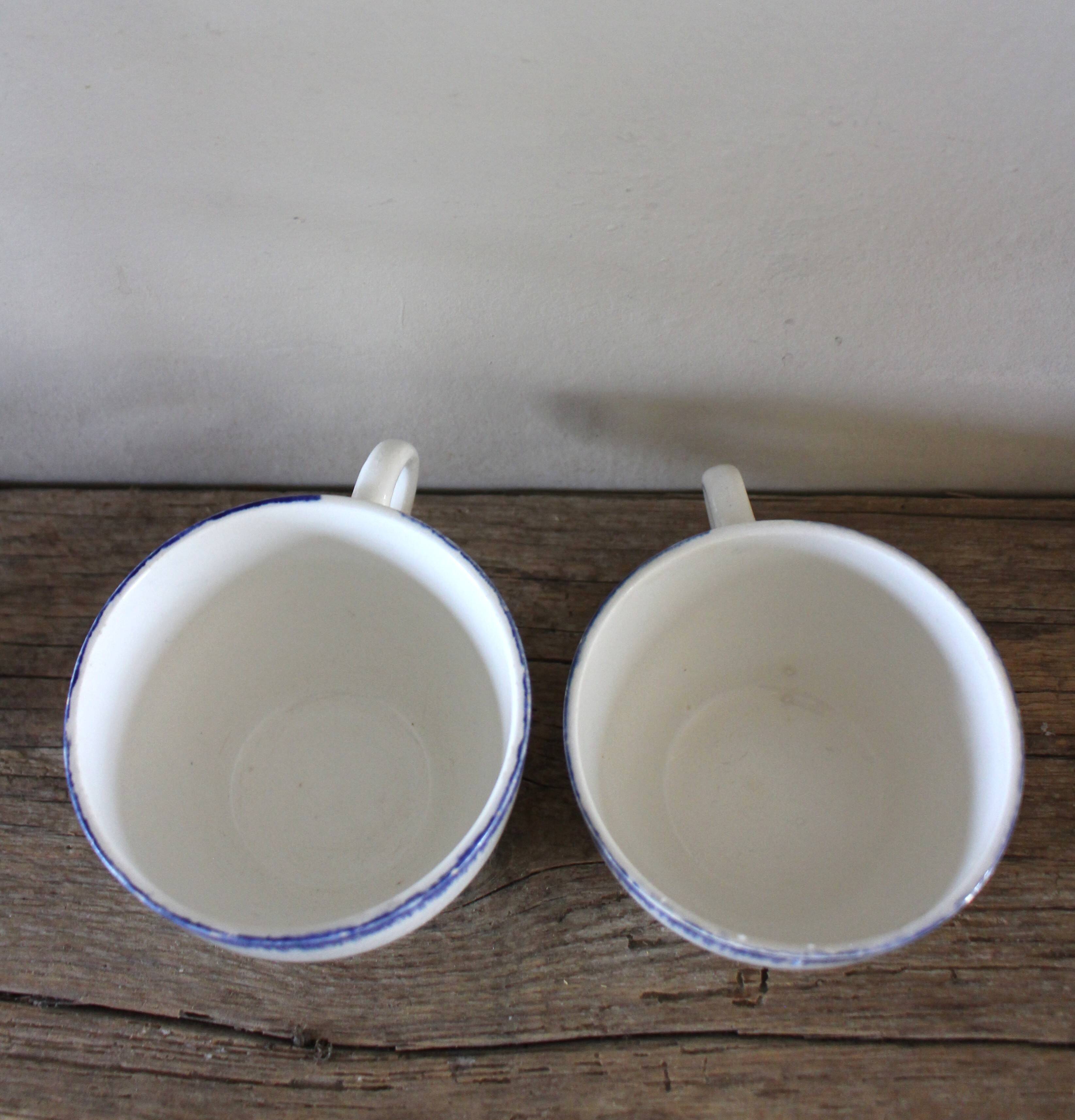 A set of two Digoin earthenware cups with blue, red, and yellow flowers.
