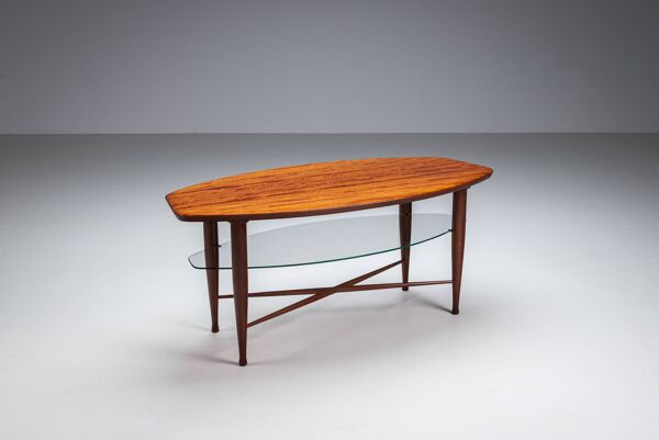 Table basse asymétrique avec rangement en verre et détails de pieds en croix.