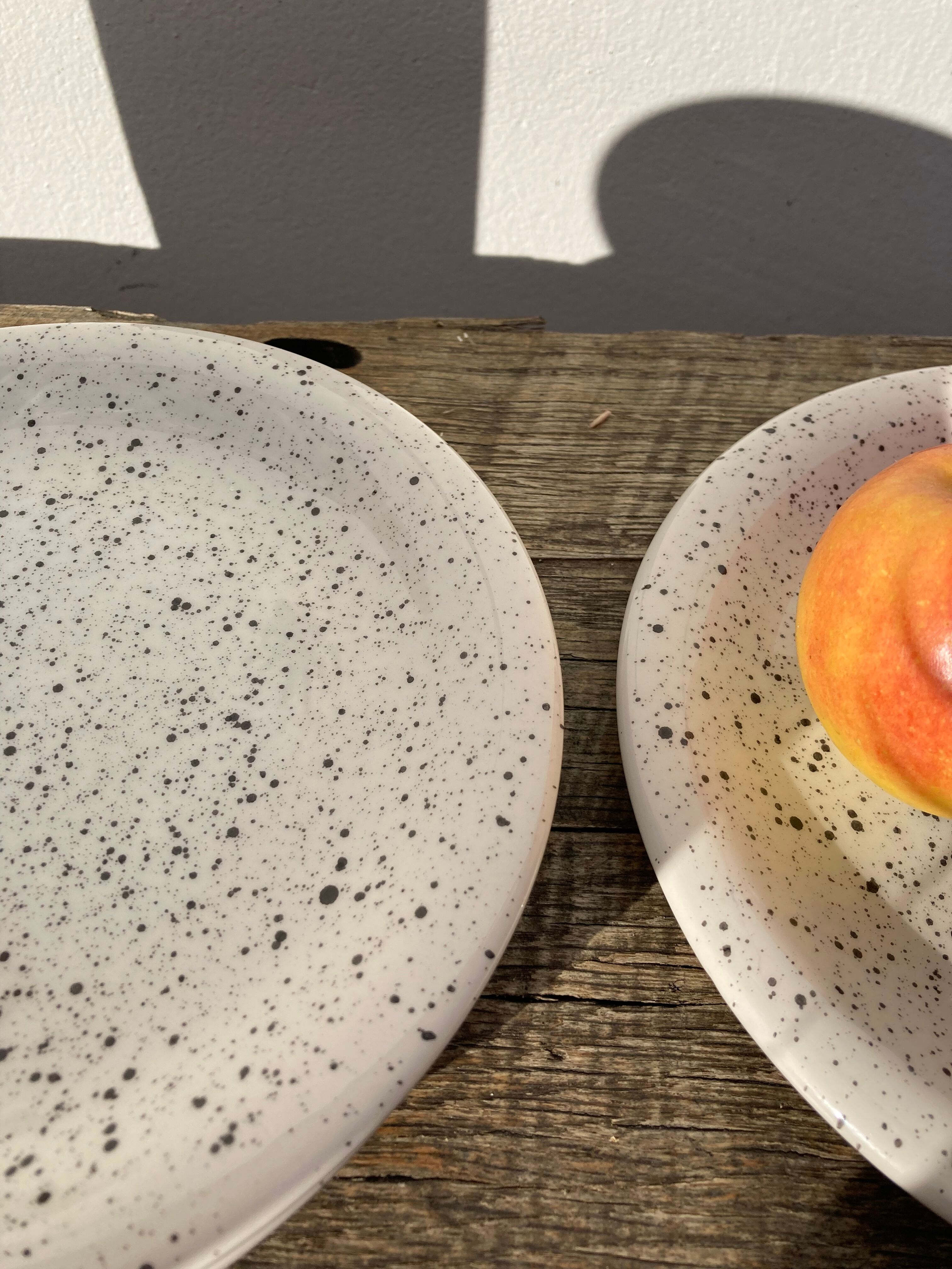 4 black speckled dessert plates on a vintage white background