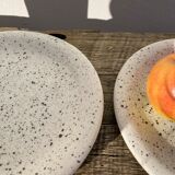 4 black speckled dessert plates on a vintage white background