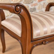 Two-seater bench in carved wood, with curved armrests.