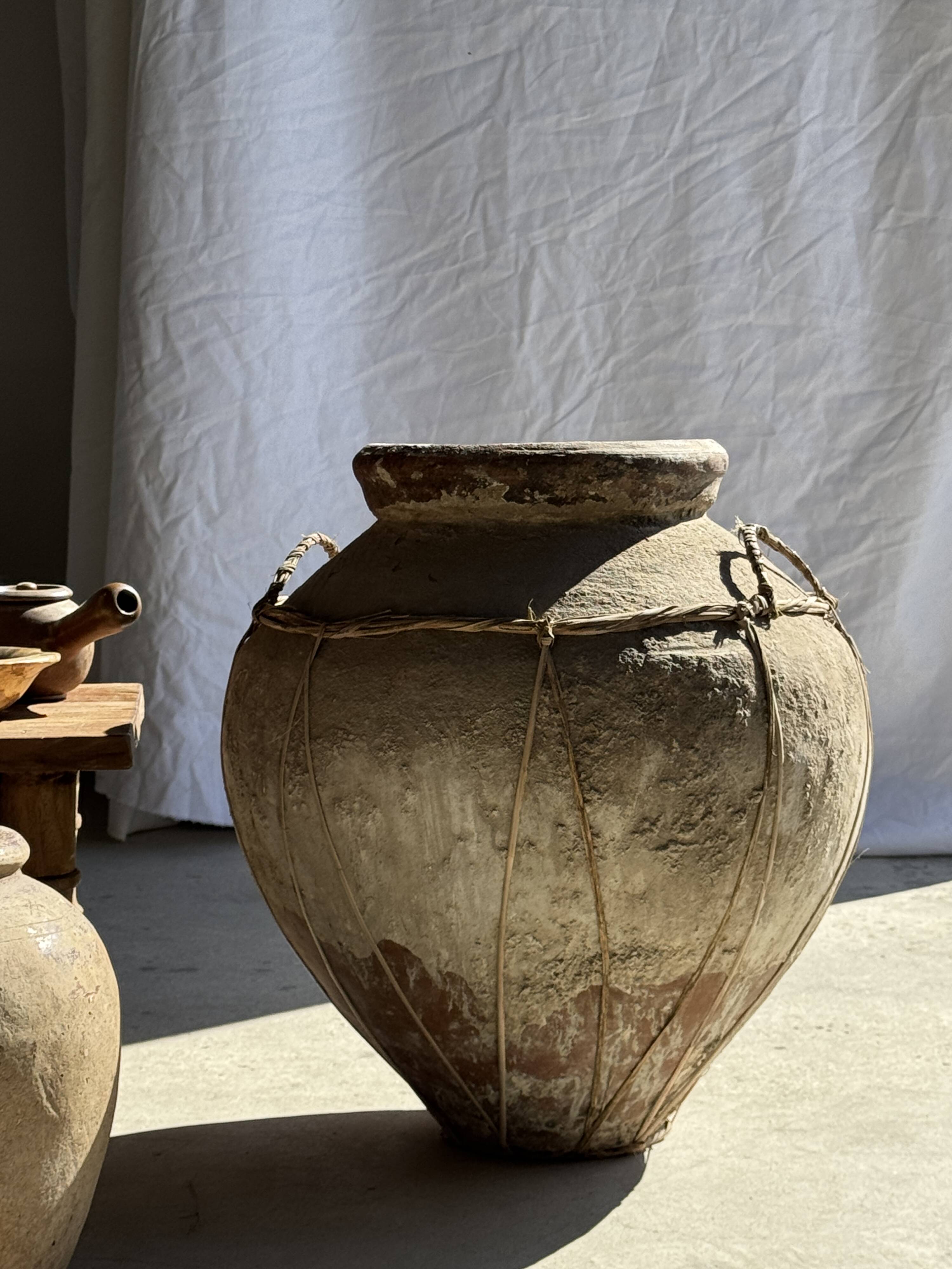Very large grey and red terracotta pot with handles and rattan crossbars.