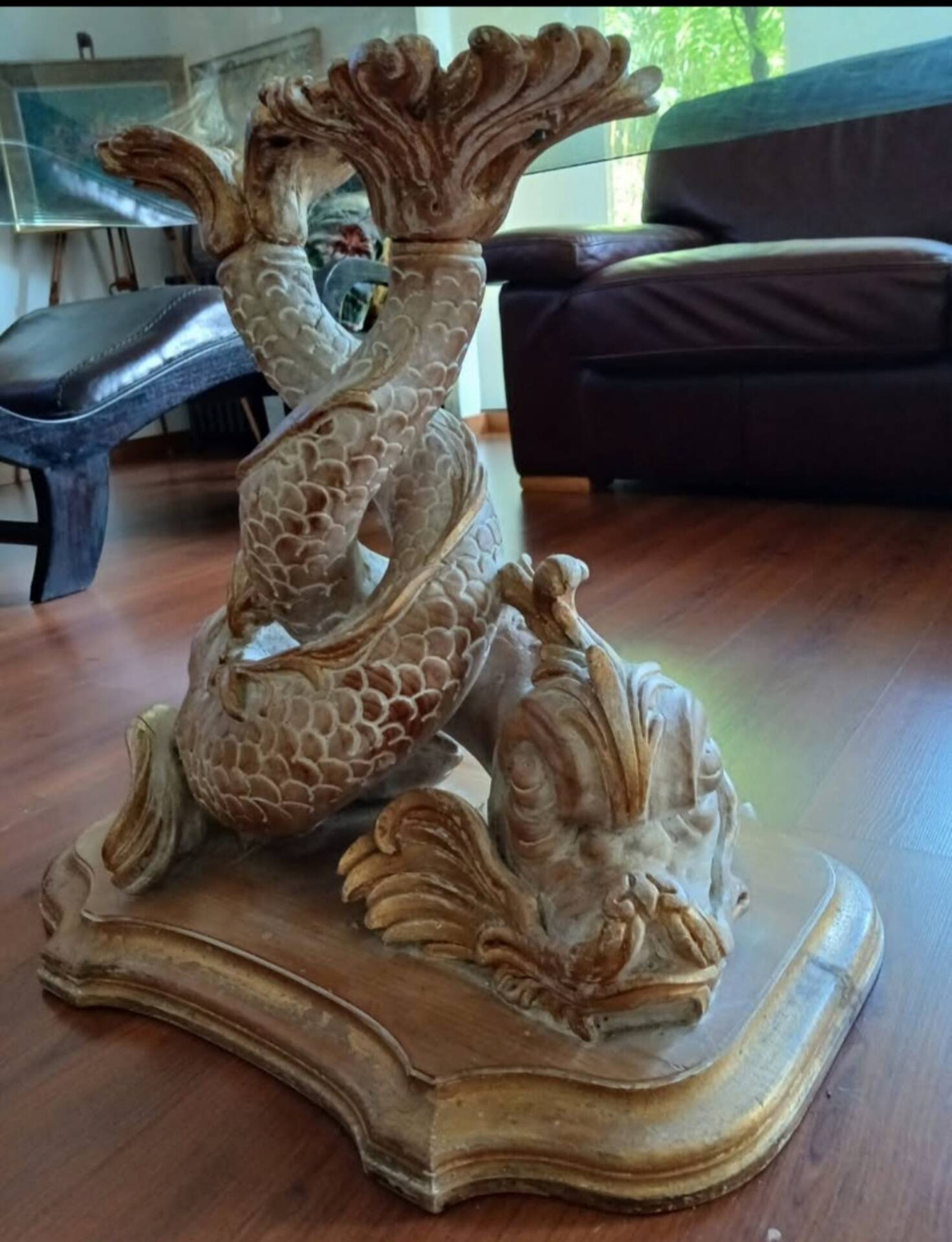Glass table with carved wooden legs featuring intertwined fish.