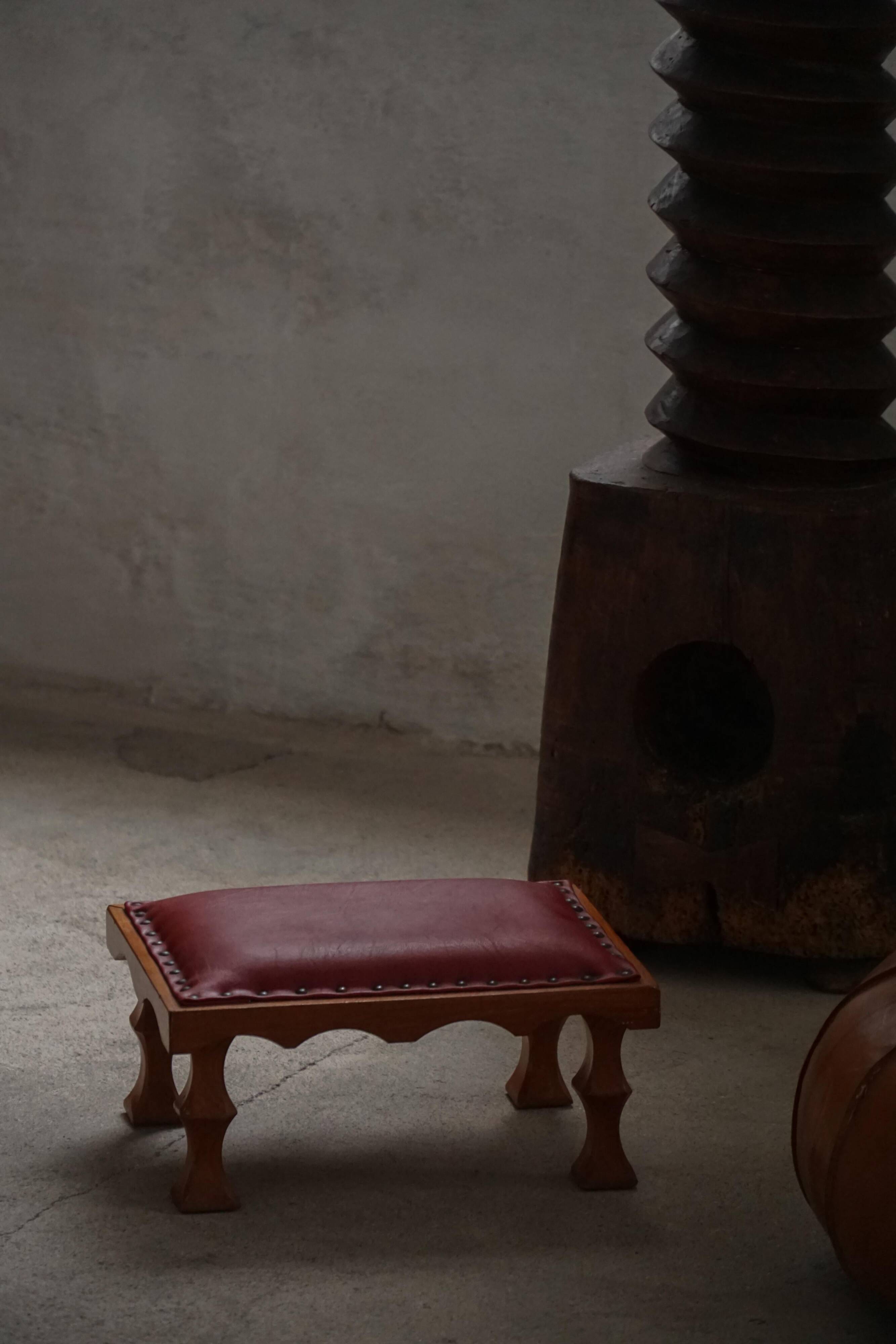 Danish sculpted oak stool from the mid-20th century with a red leather seat, 1950s.