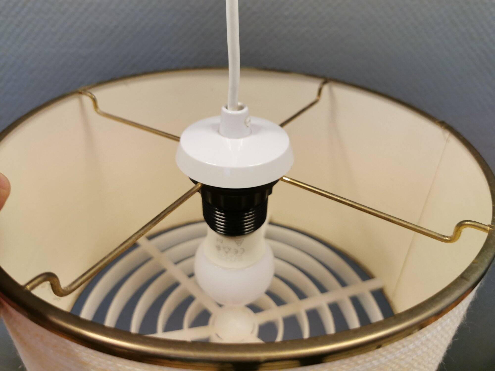 Hanging lamp with brass-coloured details, made of fabric with intact plastic bottom grille.