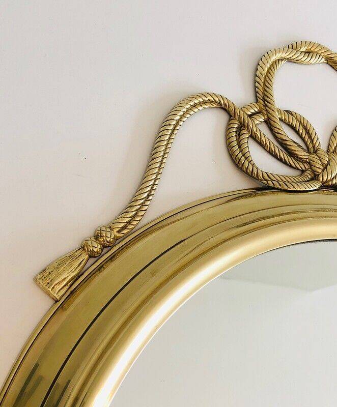 Large decorative oval mirror in brass adorned with a significant twisted bow.