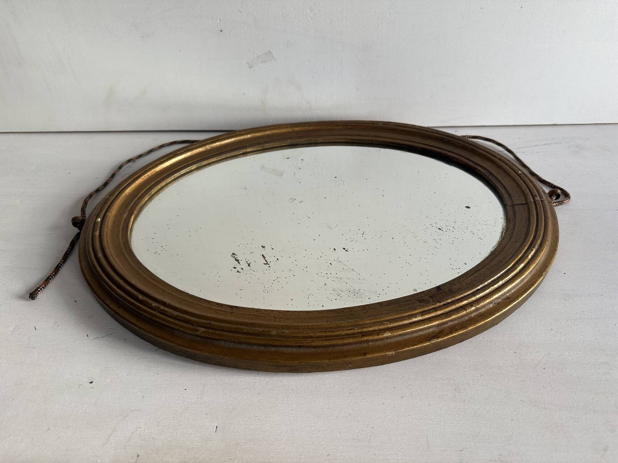 Antique oval mirror in gilded wood, bevelled mercury glass, 19th century.